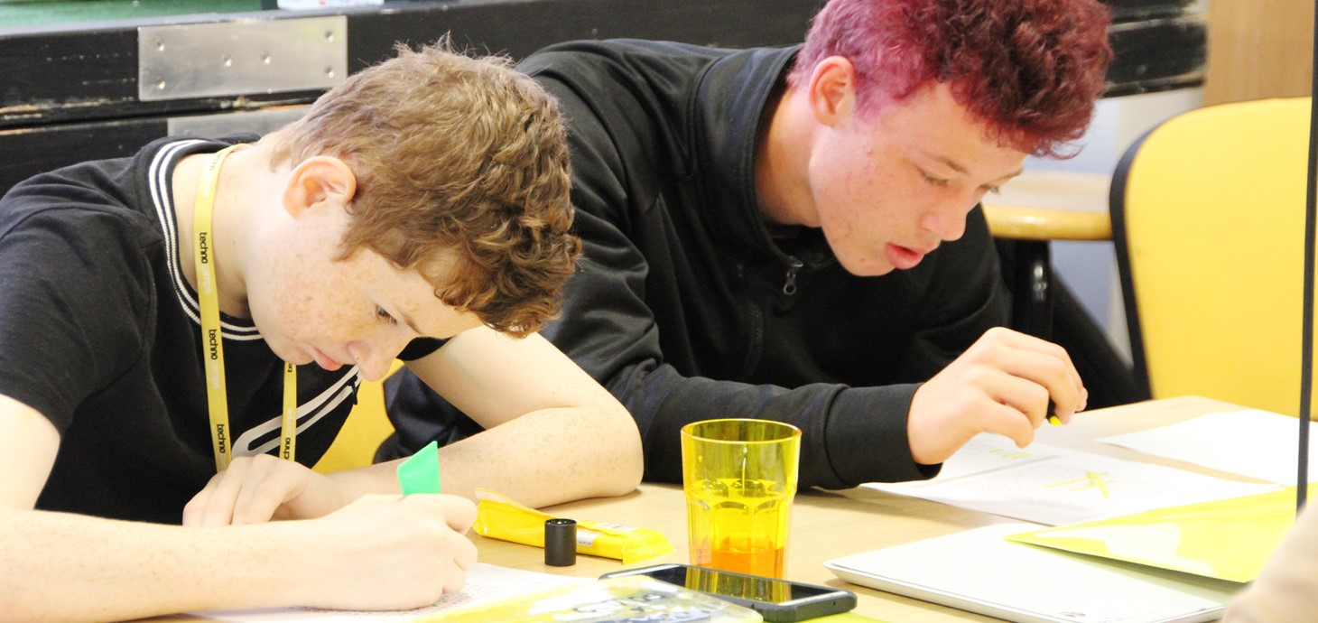 Dau ddisgybl yn gweithio mewn digwyddiad Technocamps, cyn Covid-19: bydd gweithlyfrau newydd yn galluogi disgyblion heb fynediad at y rhyngrwyd i astudio pynciau STEM hyd yn oed os bydd ysgolion ar gau.